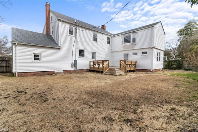 back of property with roof with shingles, a chimney, fence, and a wooden deck