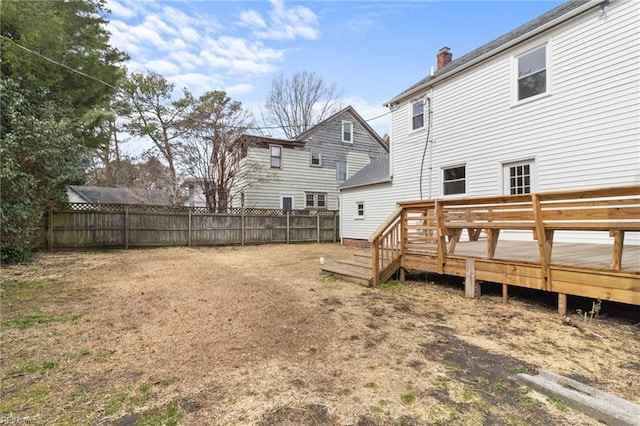 back of property with a deck, a chimney, and fence