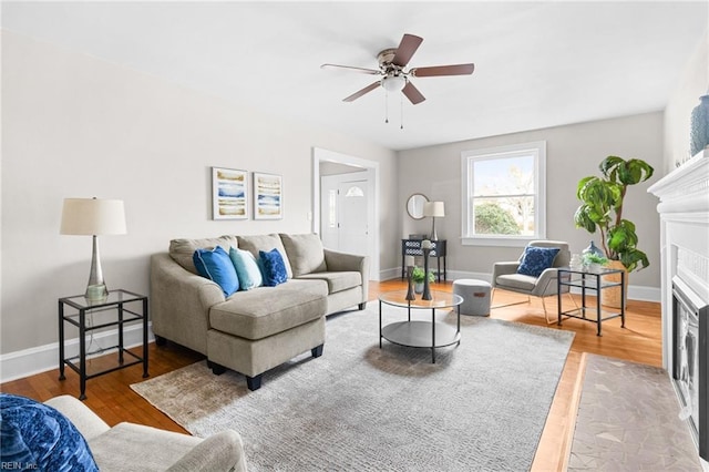 living room with a fireplace with flush hearth, baseboards, and wood finished floors