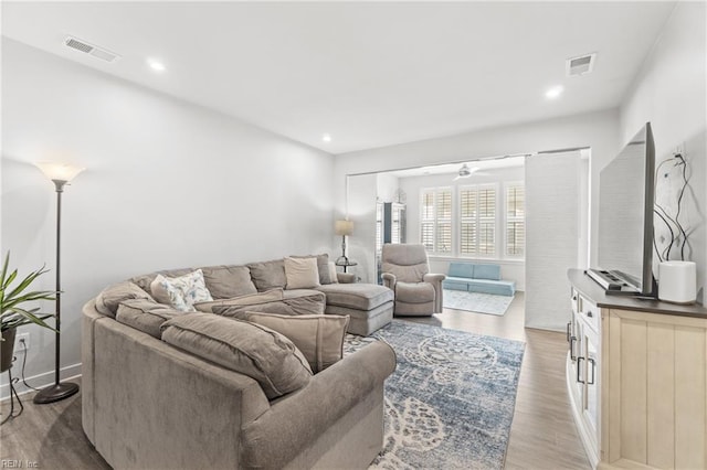 living area with light wood-type flooring, visible vents, and recessed lighting