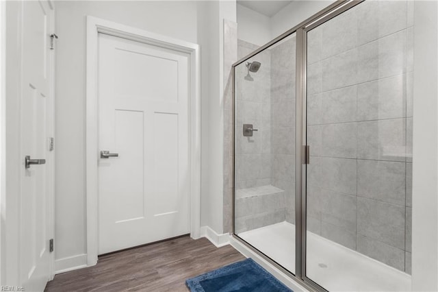 full bathroom featuring a shower stall, baseboards, and wood finished floors