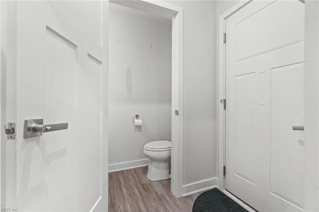 bathroom with baseboards, toilet, and wood finished floors