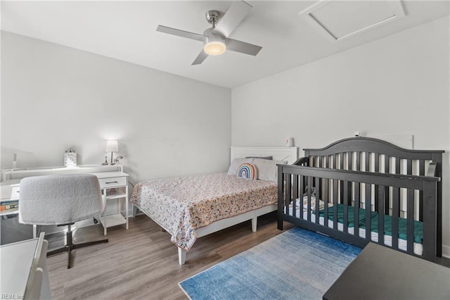 bedroom with attic access, ceiling fan, and wood finished floors