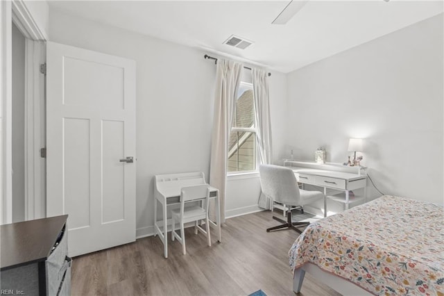 bedroom featuring visible vents, baseboards, and wood finished floors