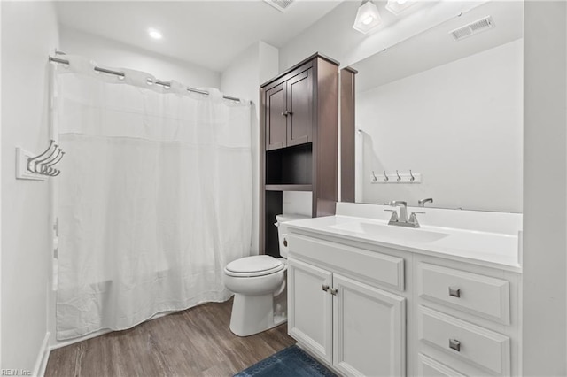 bathroom featuring visible vents, toilet, a shower with curtain, wood finished floors, and vanity