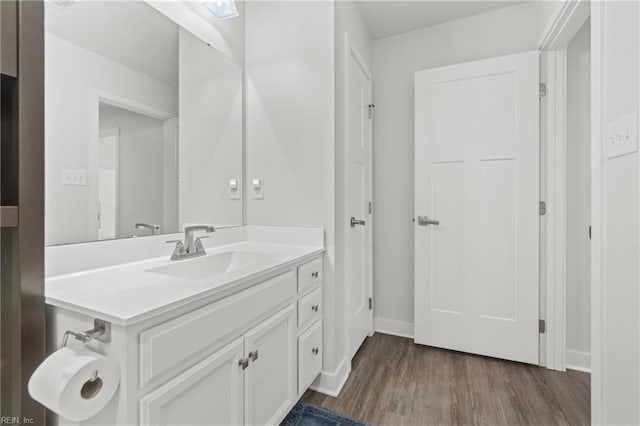 bathroom with wood finished floors, vanity, and baseboards