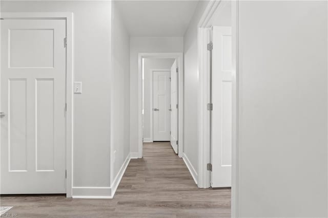 hall featuring wood finished floors and baseboards