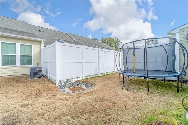 view of yard featuring a fenced backyard, a trampoline, and central AC unit