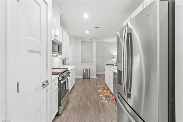 kitchen featuring light countertops, visible vents, appliances with stainless steel finishes, light wood-style floors, and white cabinets