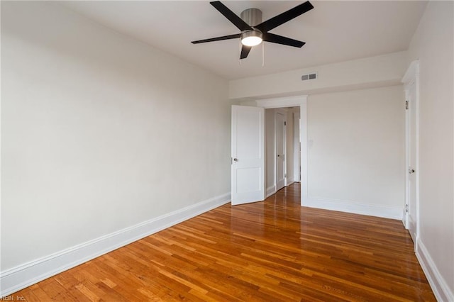 empty room featuring visible vents, baseboards, and wood finished floors