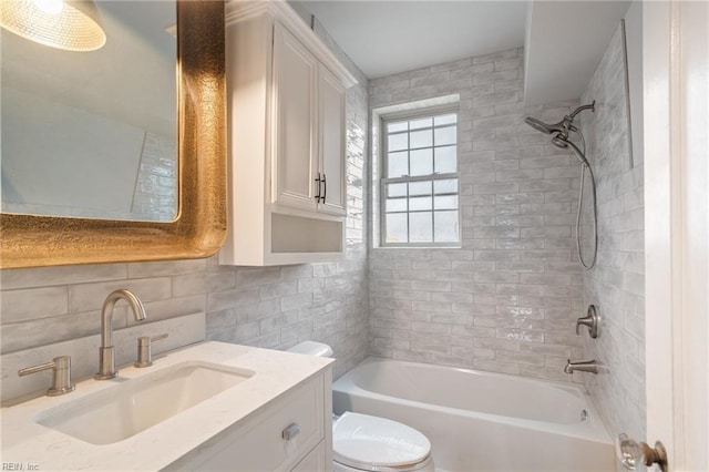 bathroom with tile walls, tasteful backsplash, toilet, washtub / shower combination, and vanity