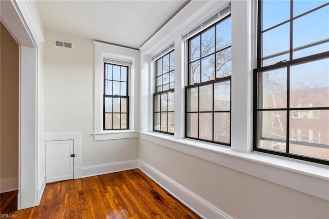 empty room featuring visible vents, baseboards, and wood finished floors