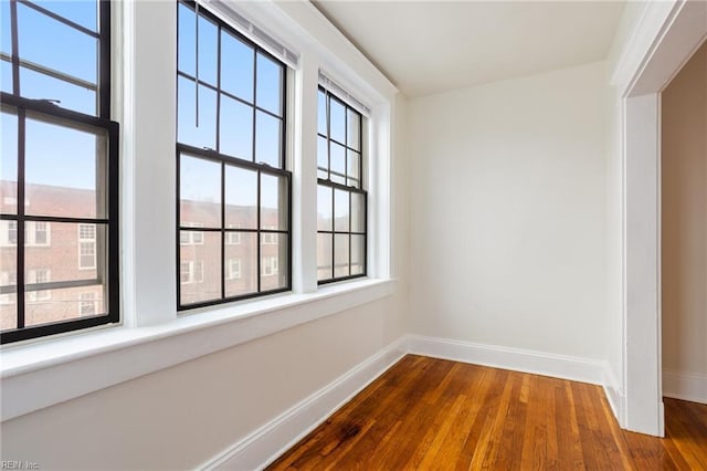 unfurnished room featuring baseboards and dark wood-style flooring