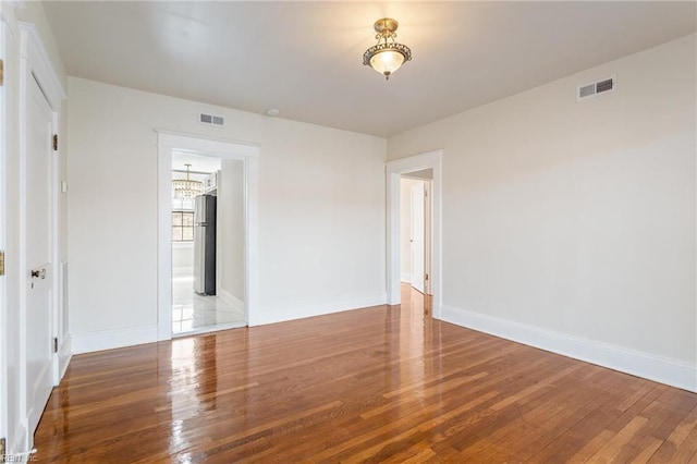 unfurnished room featuring visible vents and wood finished floors