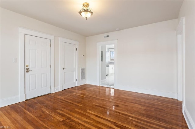 unfurnished bedroom featuring baseboards, visible vents, and wood finished floors