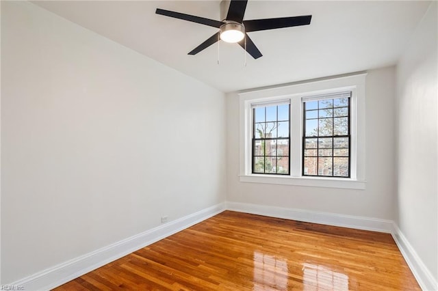 spare room featuring a ceiling fan, light wood finished floors, and baseboards