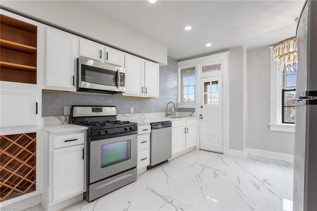 kitchen with marble finish floor, stainless steel appliances, a sink, and white cabinetry