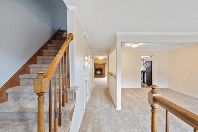 staircase with carpet floors, a fireplace, baseboards, and crown molding