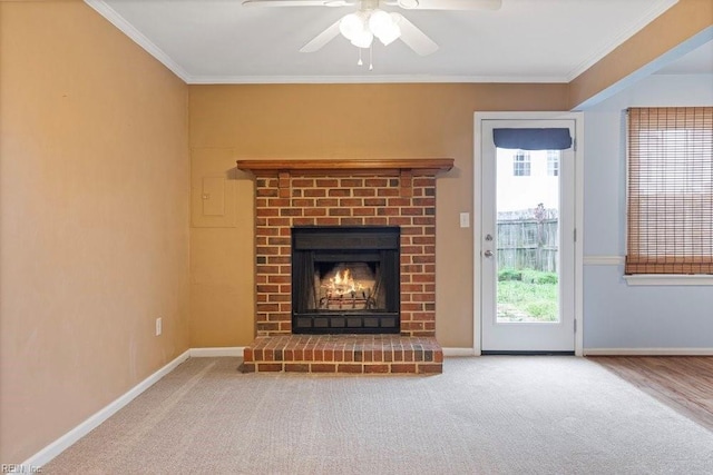 unfurnished living room with baseboards, ceiling fan, crown molding, carpet flooring, and a fireplace