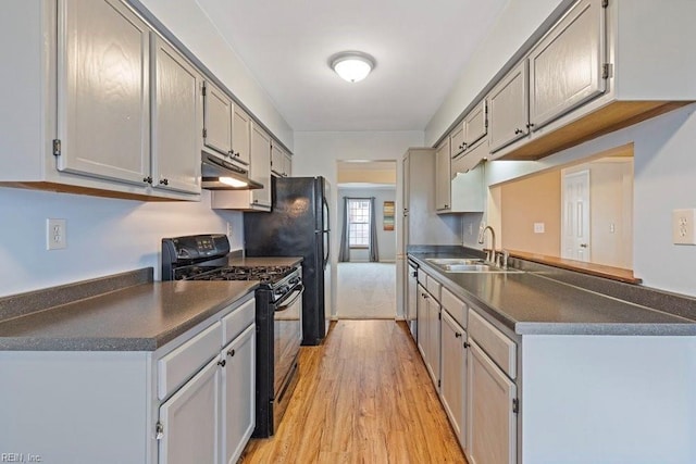 kitchen with dark countertops, black gas stove, a sink, light wood-type flooring, and under cabinet range hood