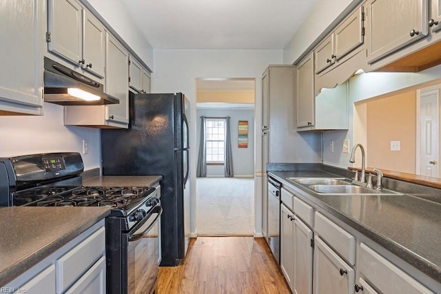 kitchen with dark countertops, black gas range, a sink, under cabinet range hood, and dishwashing machine