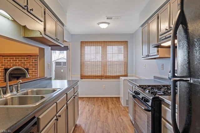 kitchen with light wood finished floors, visible vents, gas stove, freestanding refrigerator, and a sink