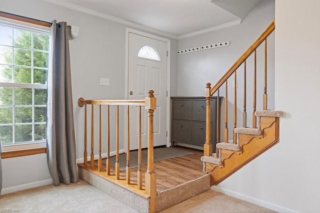 carpeted entrance foyer with baseboards, ornamental molding, and a wealth of natural light