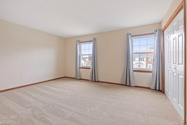 unfurnished bedroom featuring a closet, light carpet, and baseboards