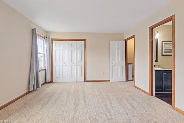 unfurnished bedroom with carpet, a closet, baseboards, and ensuite bathroom