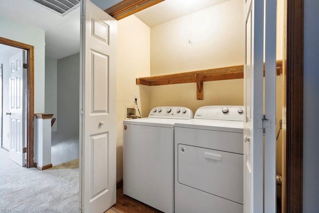 clothes washing area with laundry area, independent washer and dryer, visible vents, and light colored carpet