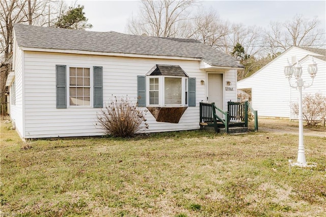 bungalow-style house with a shingled roof and a front yard