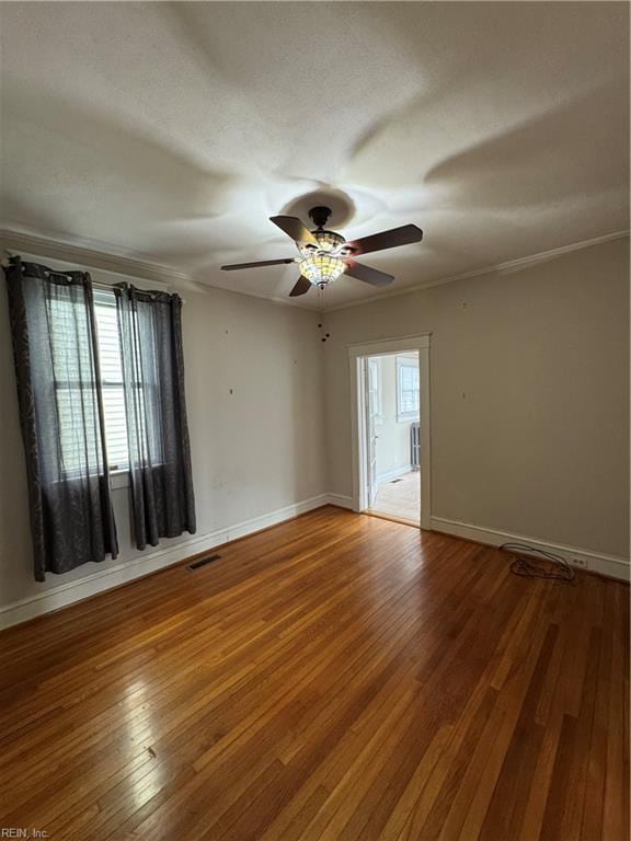 unfurnished room with hardwood / wood-style flooring, plenty of natural light, visible vents, and baseboards