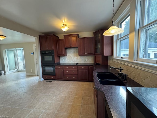 kitchen featuring dark countertops, dobule oven black, a healthy amount of sunlight, and a sink