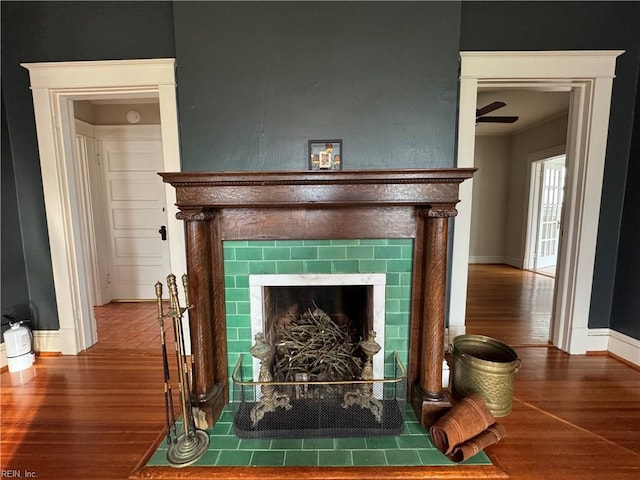 details with baseboards, a tiled fireplace, and wood finished floors