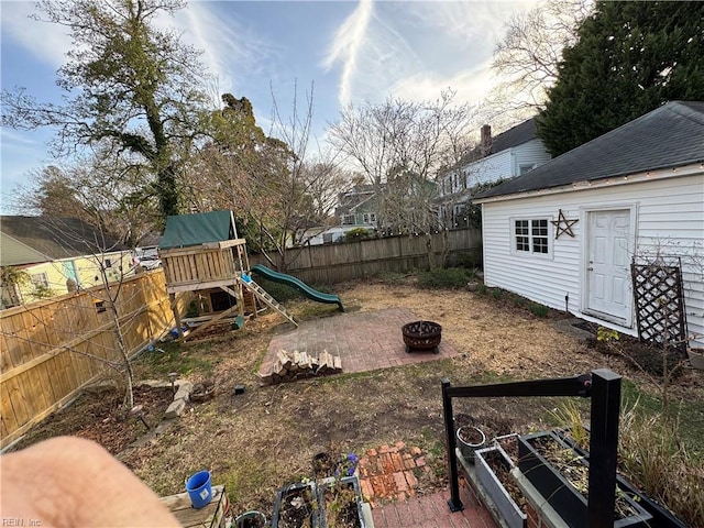 view of yard with a playground, a fire pit, and a fenced backyard