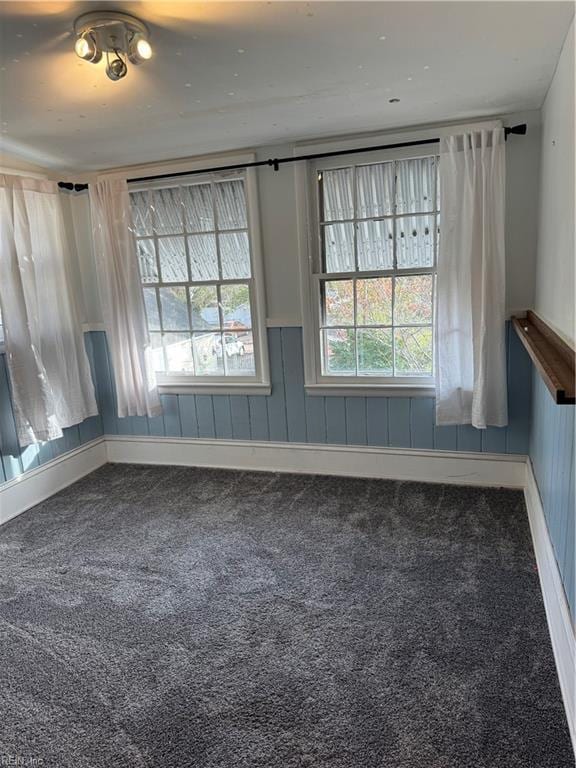 empty room featuring carpet floors and wainscoting