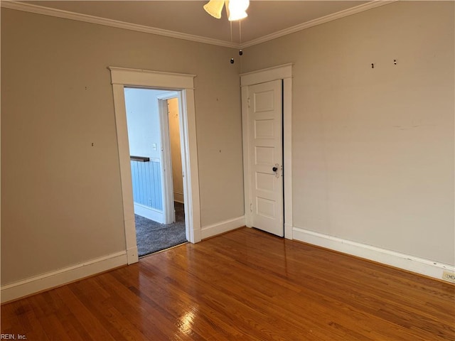 unfurnished room featuring crown molding, baseboards, and wood finished floors