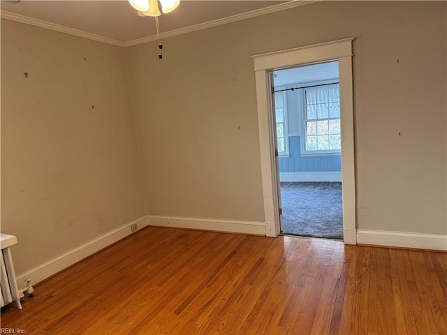 spare room featuring ornamental molding, light wood-style floors, and baseboards