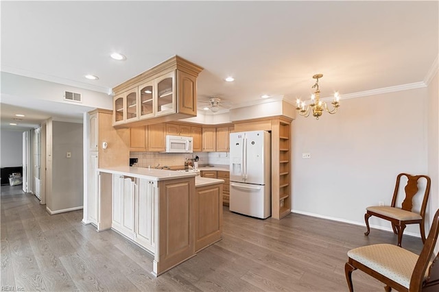 kitchen featuring light countertops, visible vents, light wood-style floors, white appliances, and a peninsula