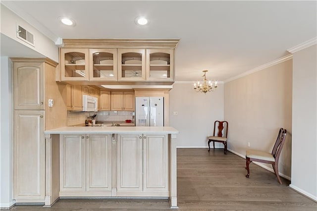 kitchen with a peninsula, white appliances, visible vents, ornamental molding, and glass insert cabinets