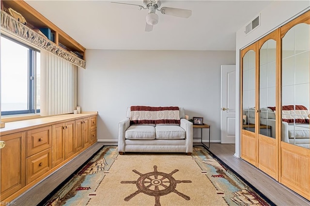 sitting room featuring visible vents, ceiling fan, baseboards, and wood finished floors