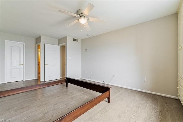 spare room with a ceiling fan, wood finished floors, visible vents, and baseboards