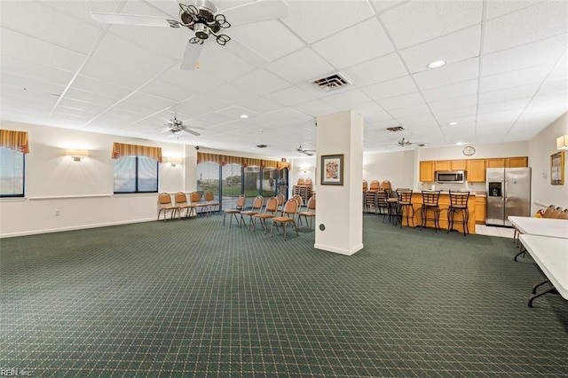 gym with visible vents, baseboards, a ceiling fan, a drop ceiling, and dark carpet