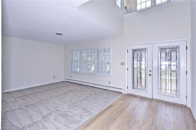 entryway with french doors, visible vents, a baseboard heating unit, a textured ceiling, and wood finished floors