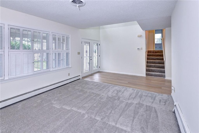 carpeted empty room featuring stairway, visible vents, a baseboard heating unit, and a textured ceiling