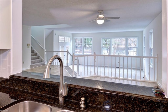 kitchen featuring ceiling fan, dark stone counters, and a sink