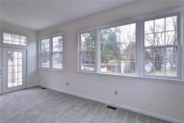 carpeted empty room with visible vents, a textured ceiling, and baseboards