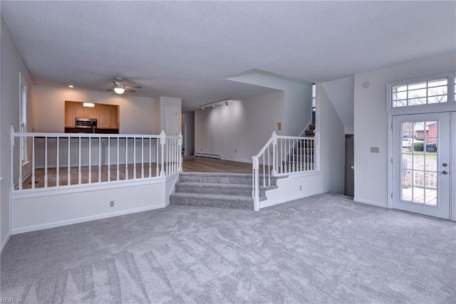 foyer featuring carpet, stairway, baseboard heating, and a textured ceiling