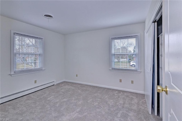 interior space with a baseboard heating unit, carpet, visible vents, and baseboards