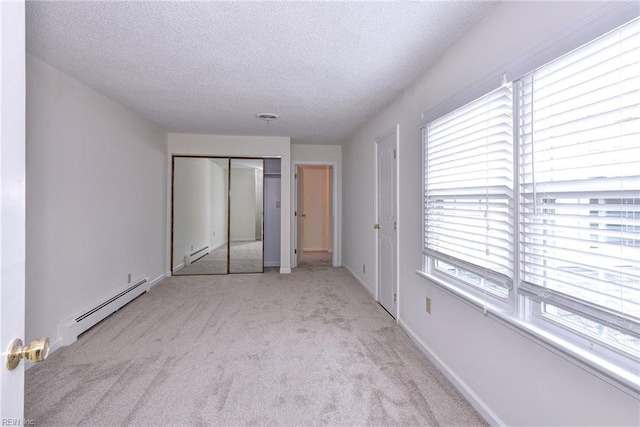 unfurnished bedroom featuring a baseboard heating unit, carpet, a textured ceiling, and baseboards